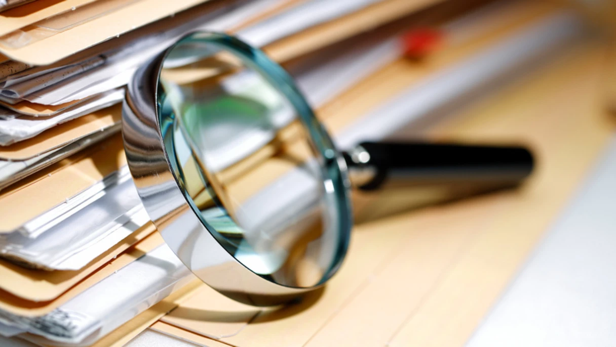 A magnifying glass on a stack of files