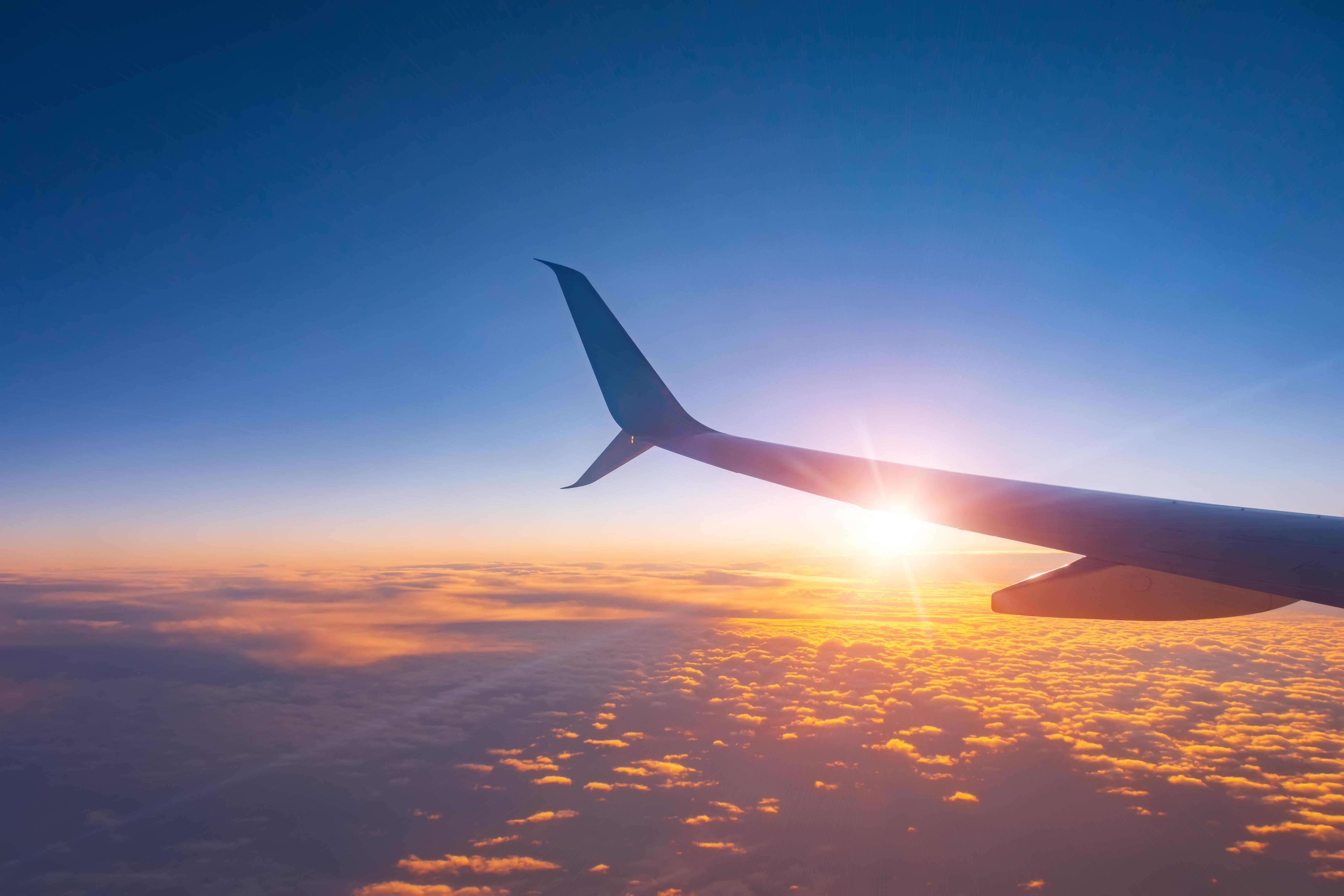 Airplane window at sunset, highlighting the wing and winglet