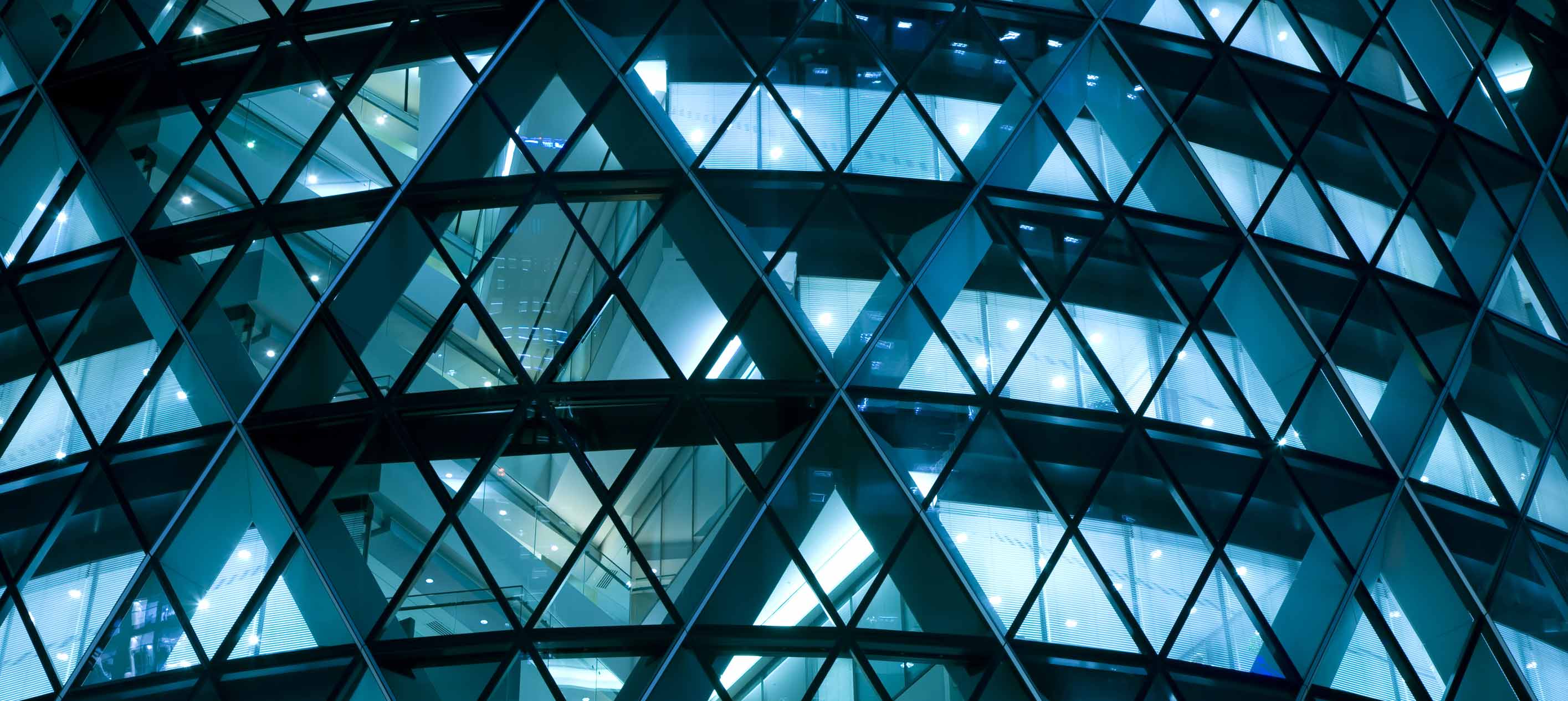 Geometric glass facade lit at night.