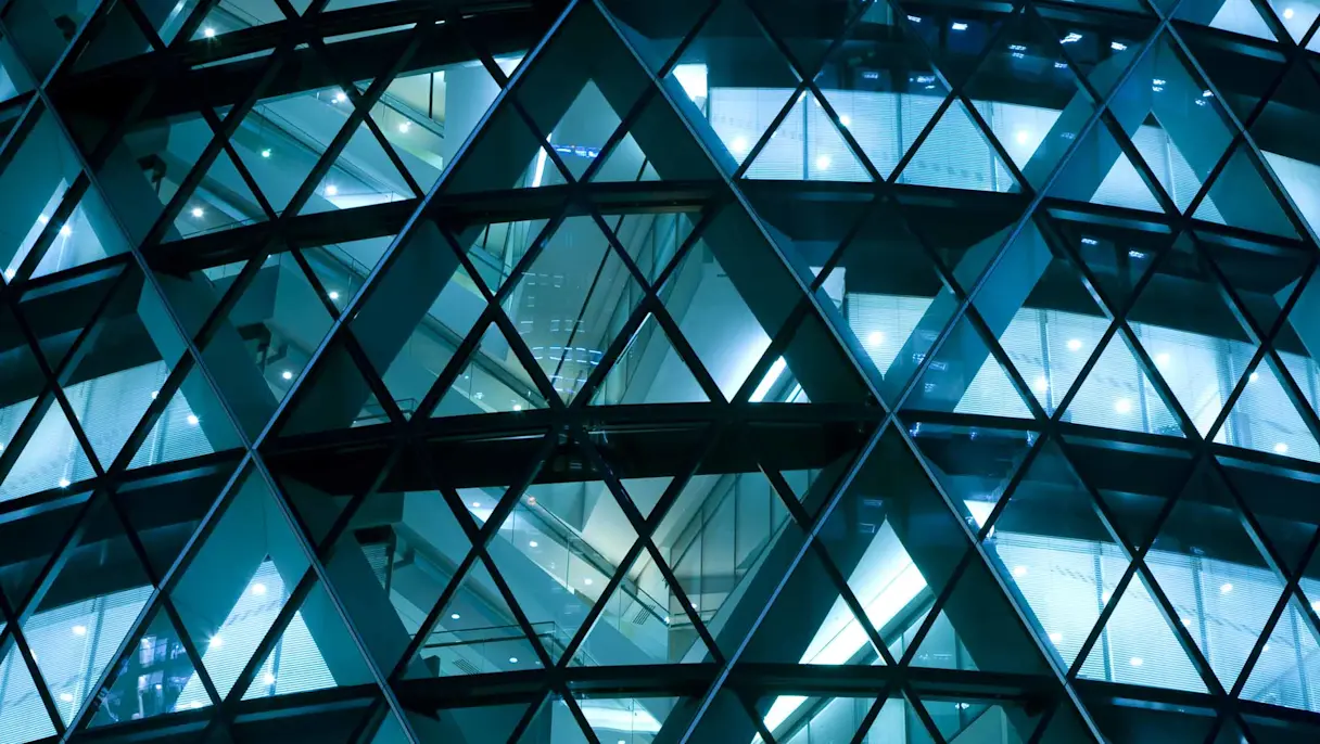 Geometric glass facade lit at night.