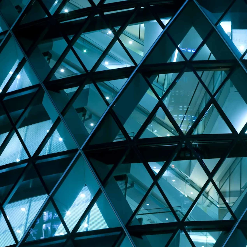 Geometric glass facade lit at night.