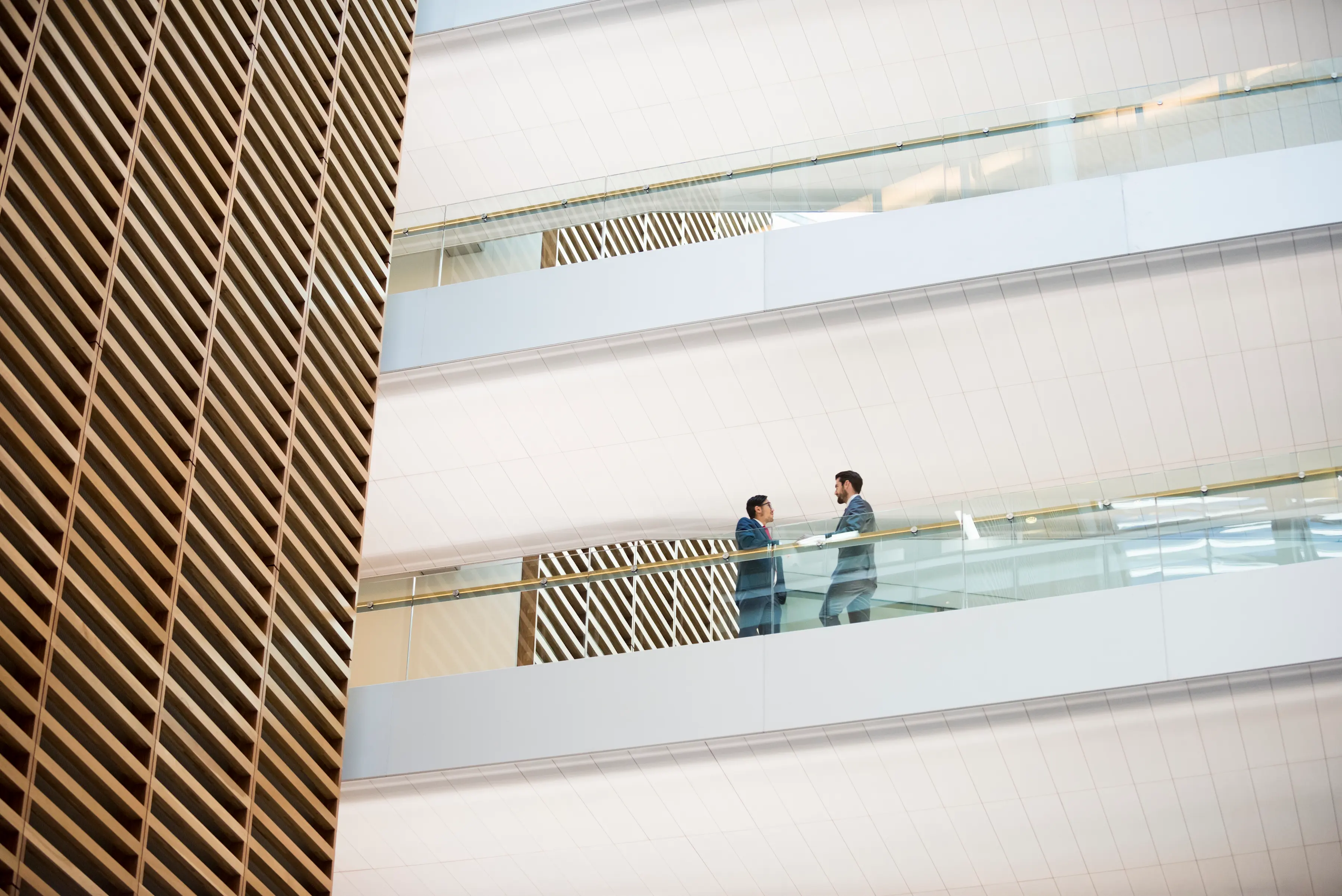 Two men in suits facing each other in a large corporate building