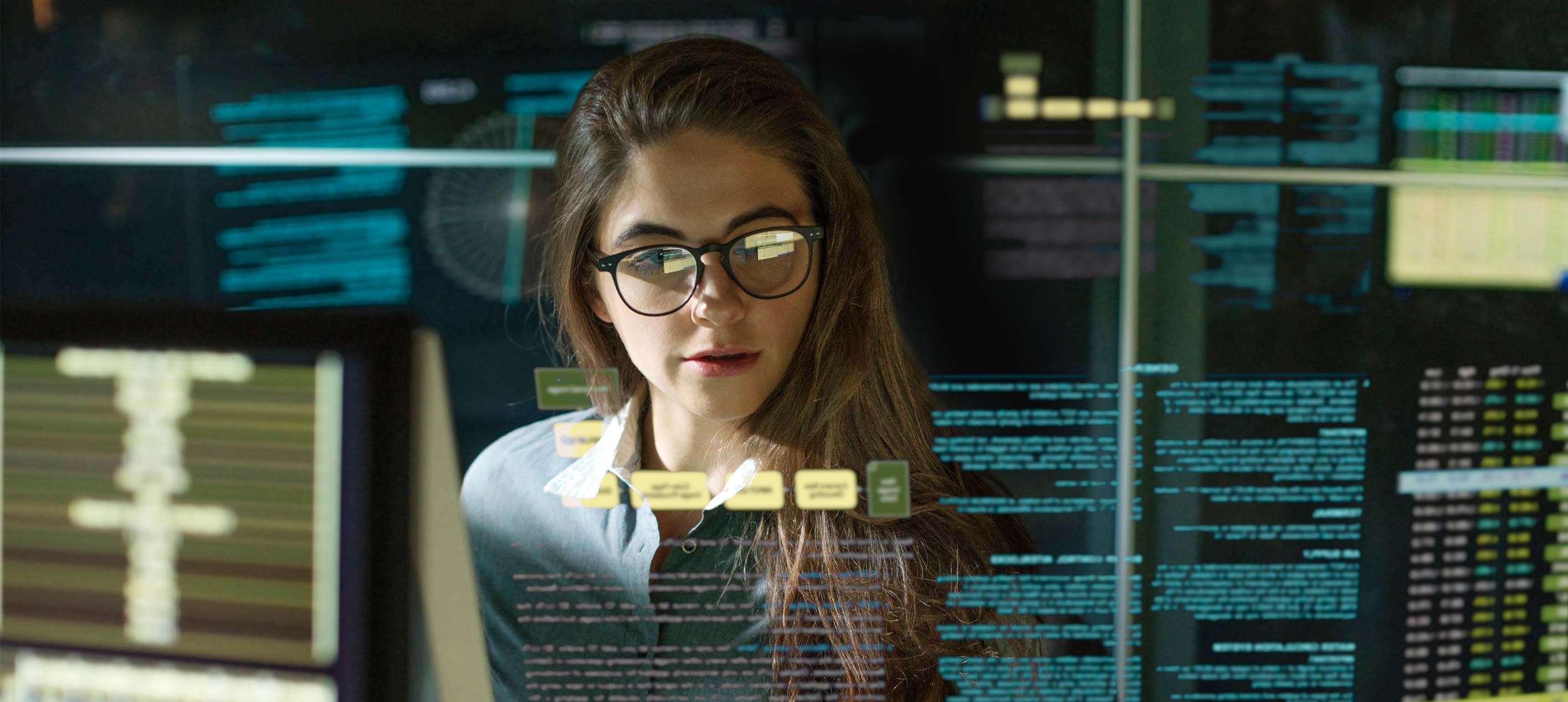 A professional woman wearing glasses analyzing digital data displays and charts on a transparent screen.
