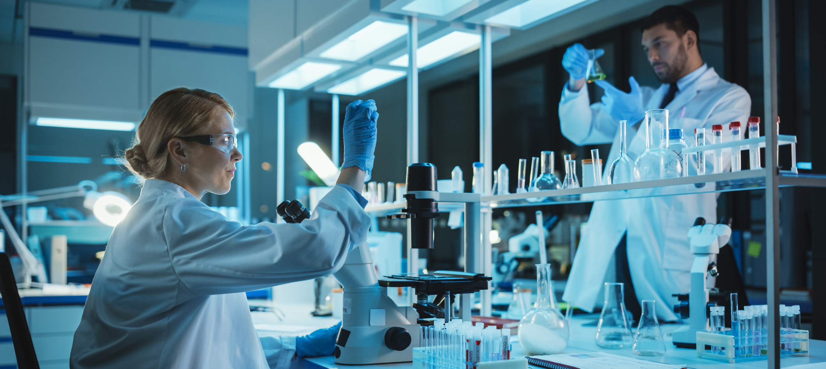 Two chemist in white lab coat conducting an experiment 