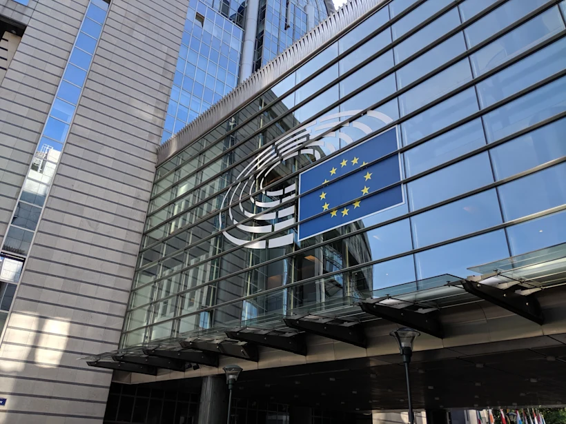 Glass facade of a modern building displaying the European Union flag with twelve gold stars in a circle on a blue background.