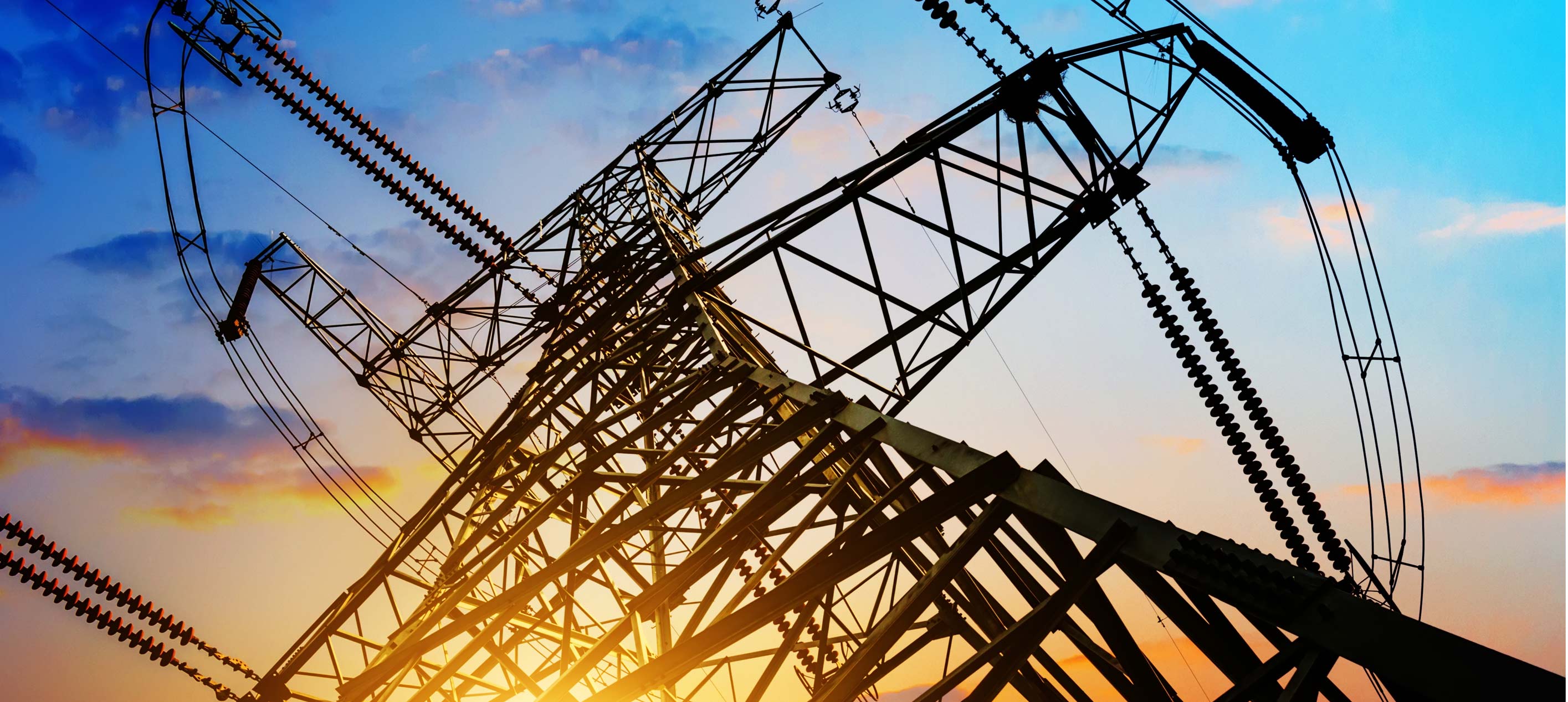 Silhouette of an electricity transmission tower at sunset, showcasing energy infrastructure against a vibrant sky.