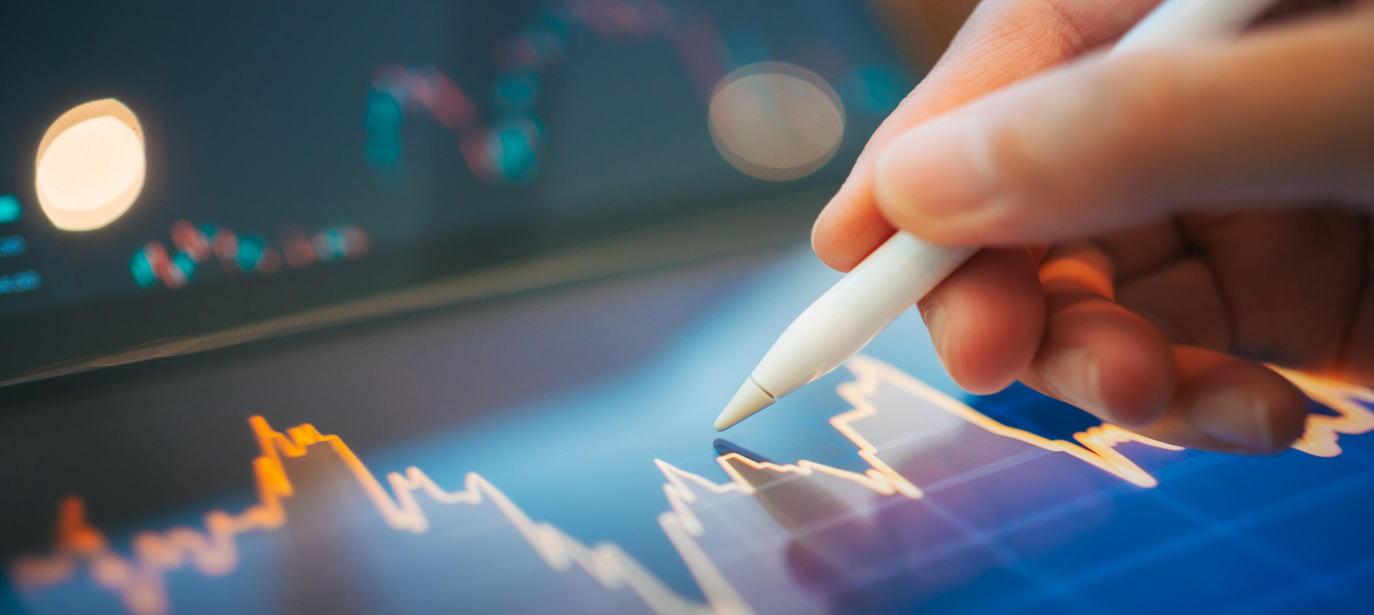 person using a stylus to analyze digital stock market charts and financial data on a tablet.