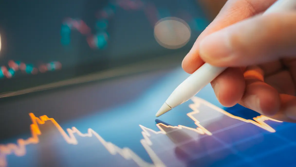 person using a stylus to analyze digital stock market charts and financial data on a tablet.