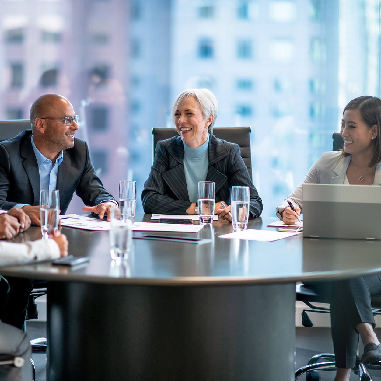 A group of people sitting around a table smiling