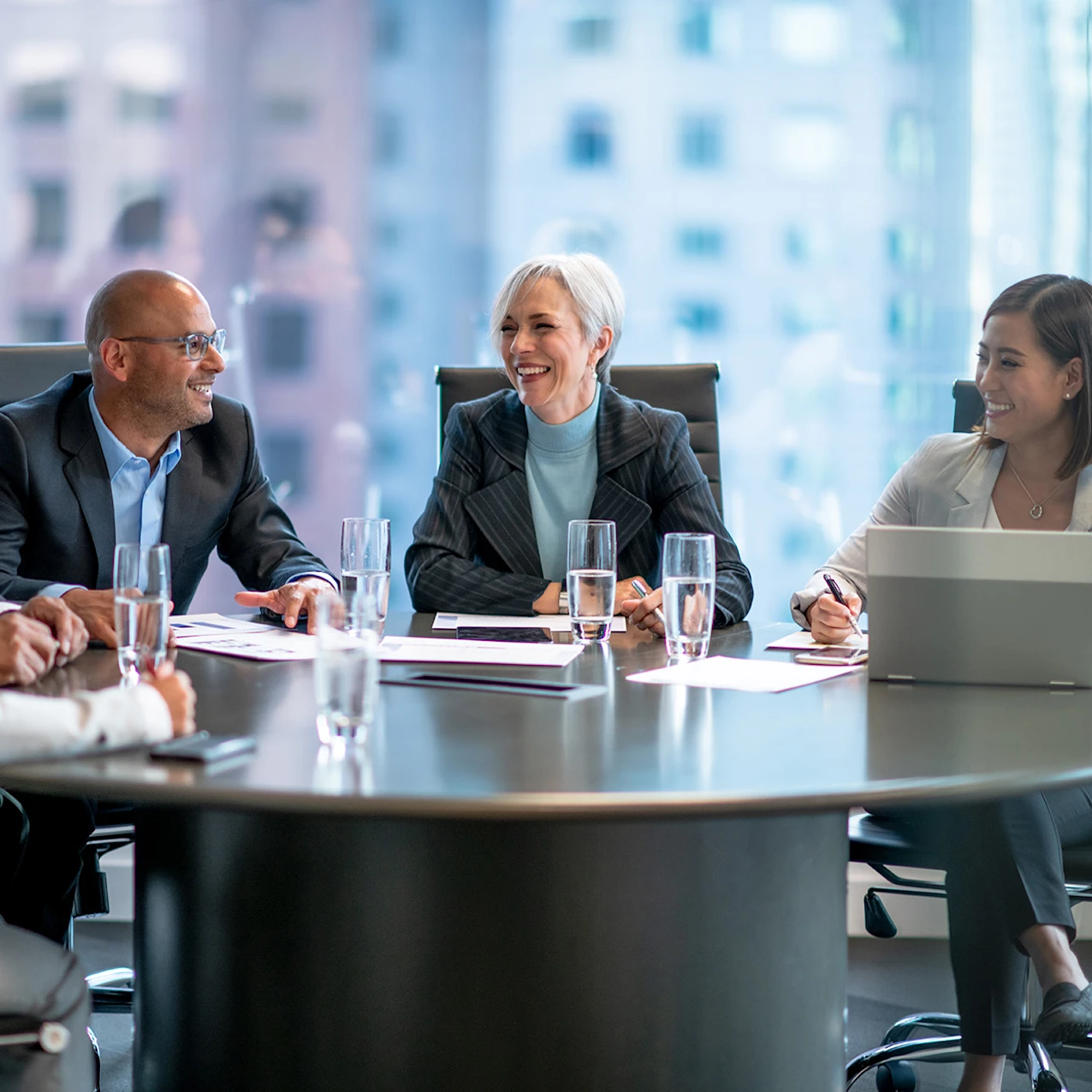 A group of people sitting around a table smiling