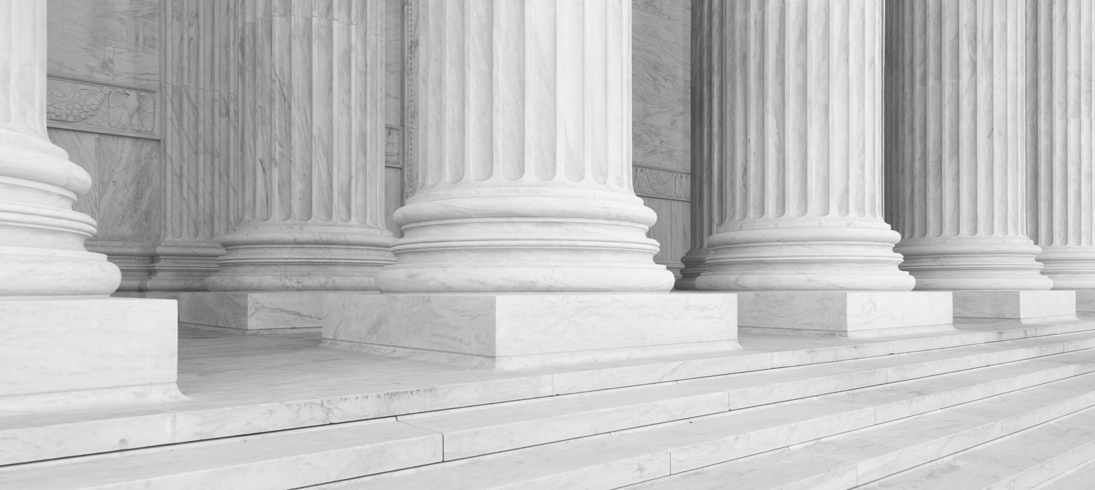 Close-up of large white marble columns and steps at a classical-style government or courthouse building.