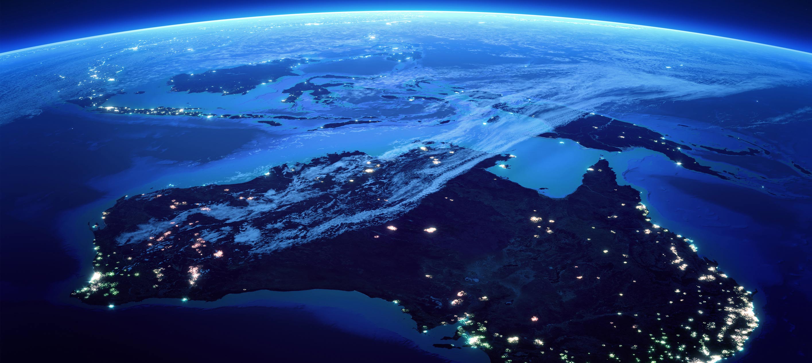 Satellite view of Australia at night, showing illuminated cities and surrounding ocean.