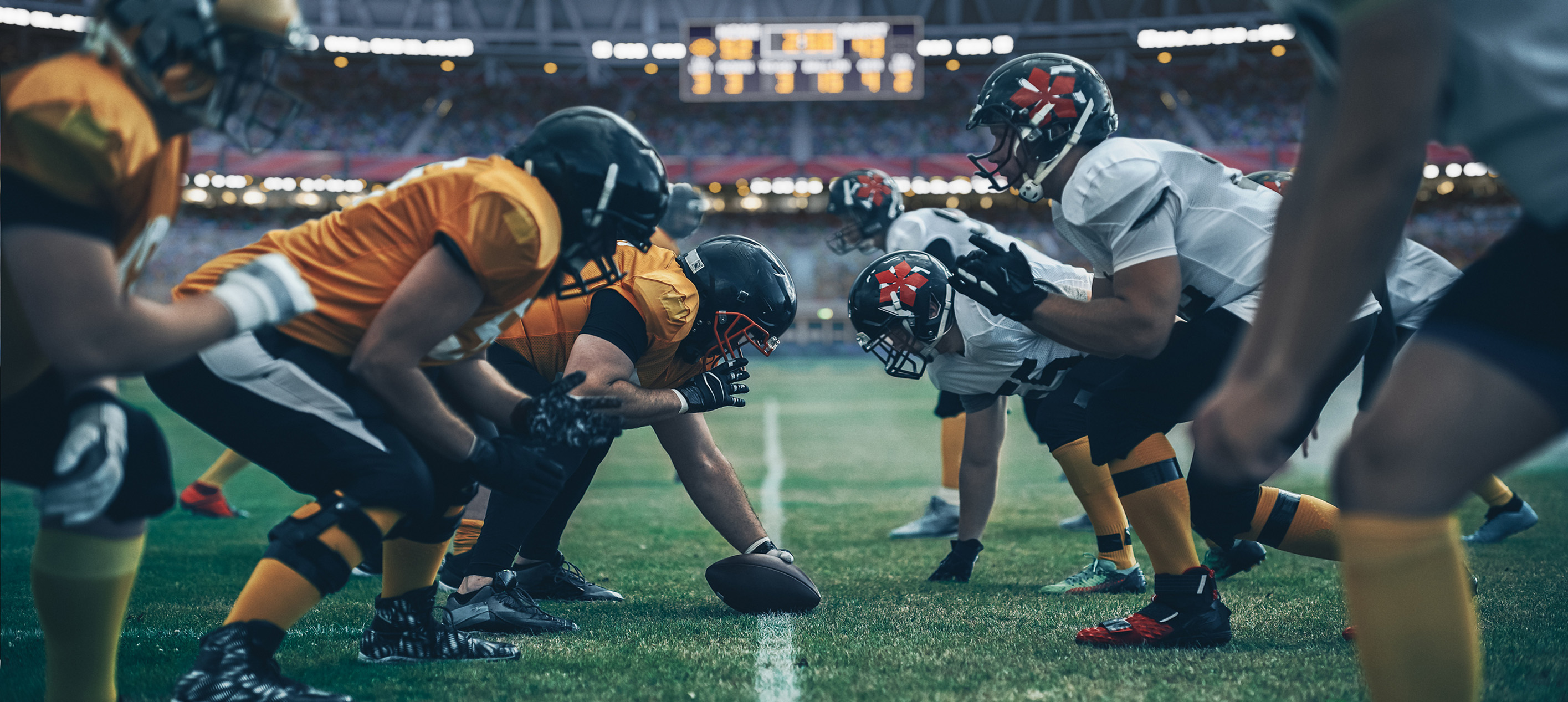 American football players line up at the line of scrimmage before the snap.
