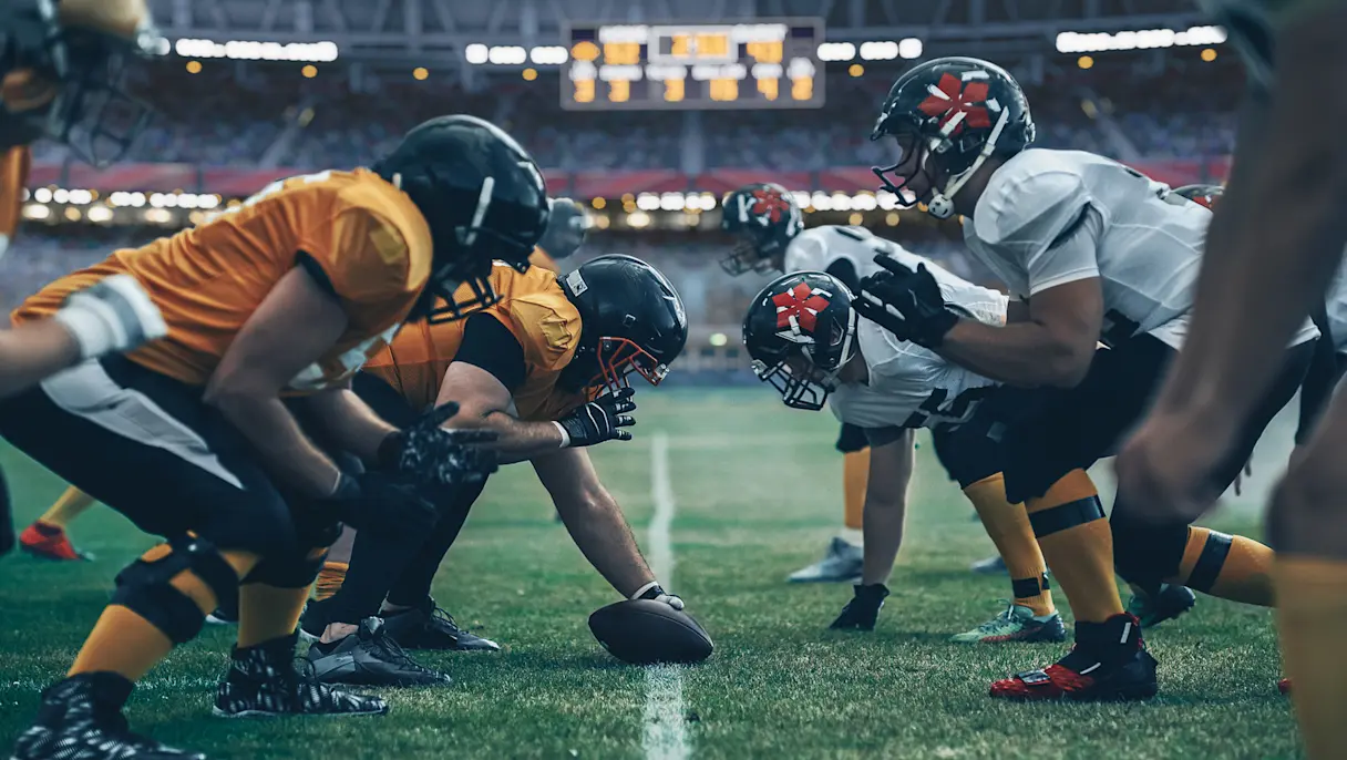 American football players line up at the line of scrimmage before the snap.