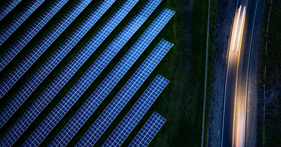 Rows of solar panels next to road at night