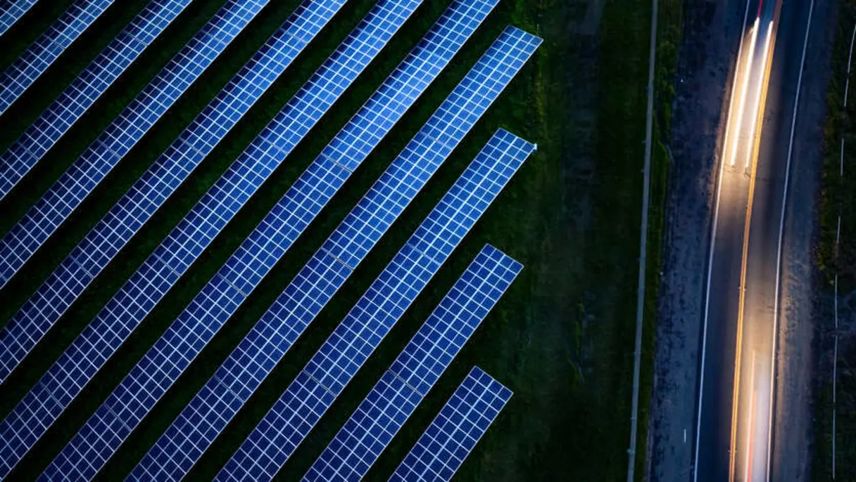 Rows of solar panels next to road at night