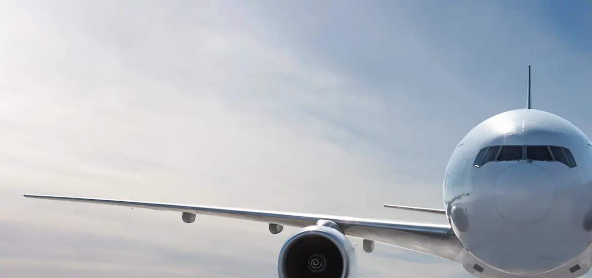 White commercial jet airliner flying above a dense layer of clouds