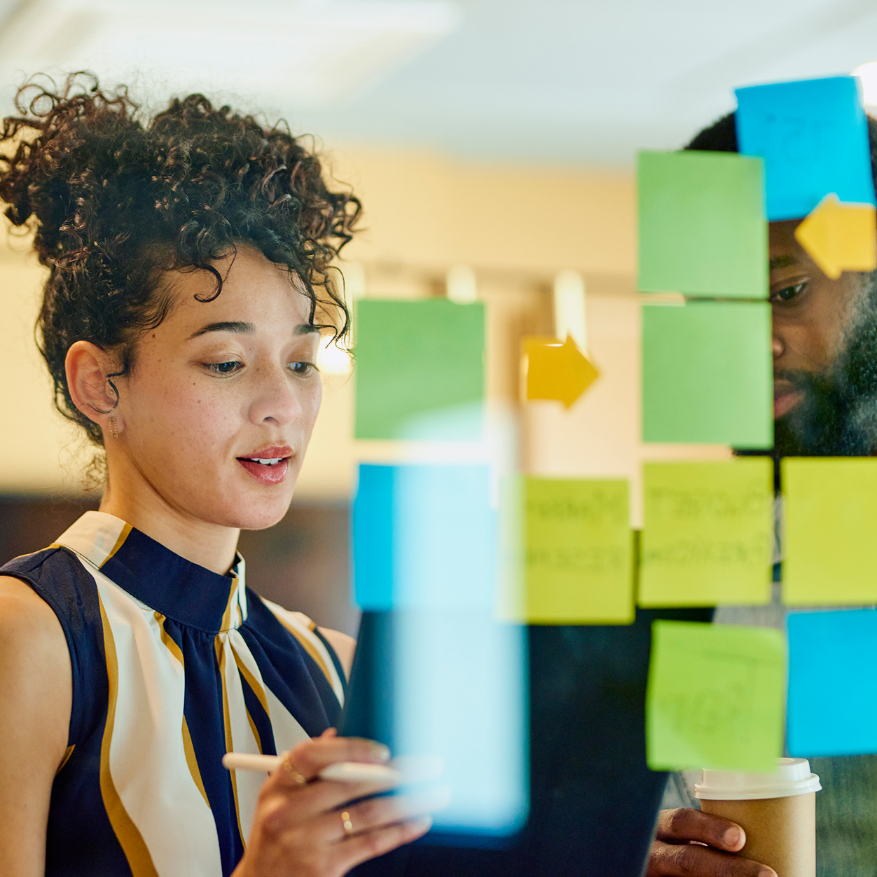 Person looking at colourful sticky-notes on a clear glass window