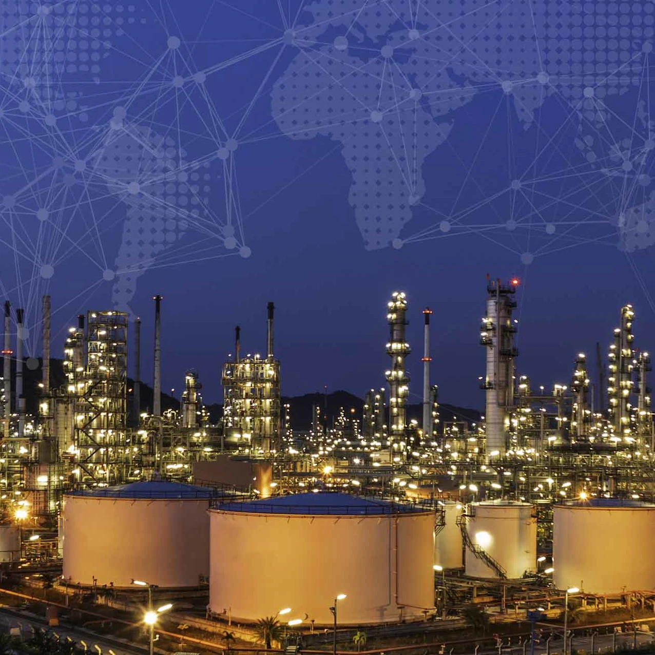 Nighttime view of an illuminated industrial refinery with large storage tanks and towers against a dark blue sky and faint network map overlay.