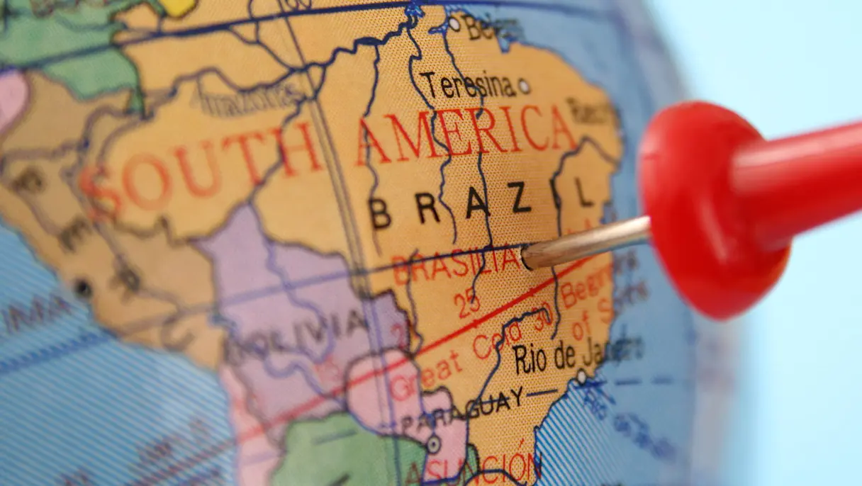 Close-up of a map of South America with a red pushpin marking Brazil, near Brasília and Rio de Janeiro.