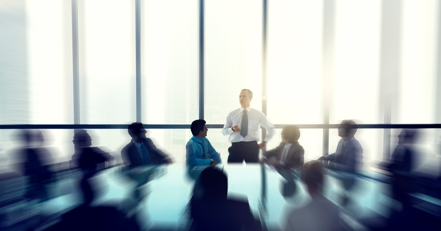 A blurred image of a group of professionals sitting at a conference table