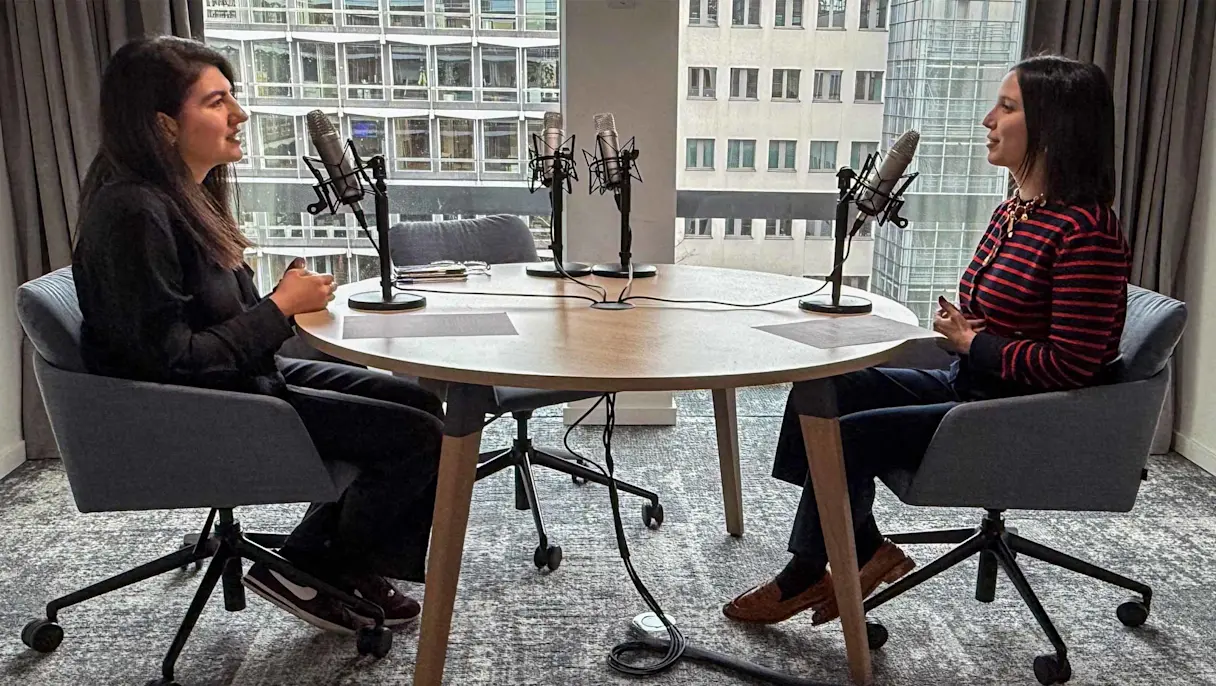 Two professionals sitting across from each other with podcast mics in front of them.