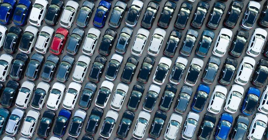Aerial view of rows of parked new cars in various colors.