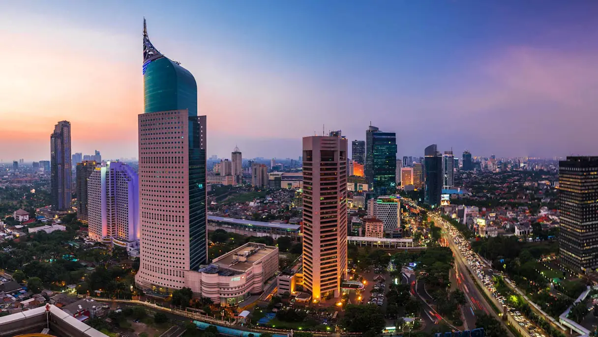 Jakarta city skyline at sunset with tall buildings and busy streets.