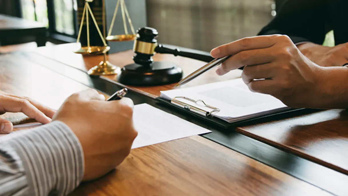 People hands signing documents on a wooden desk