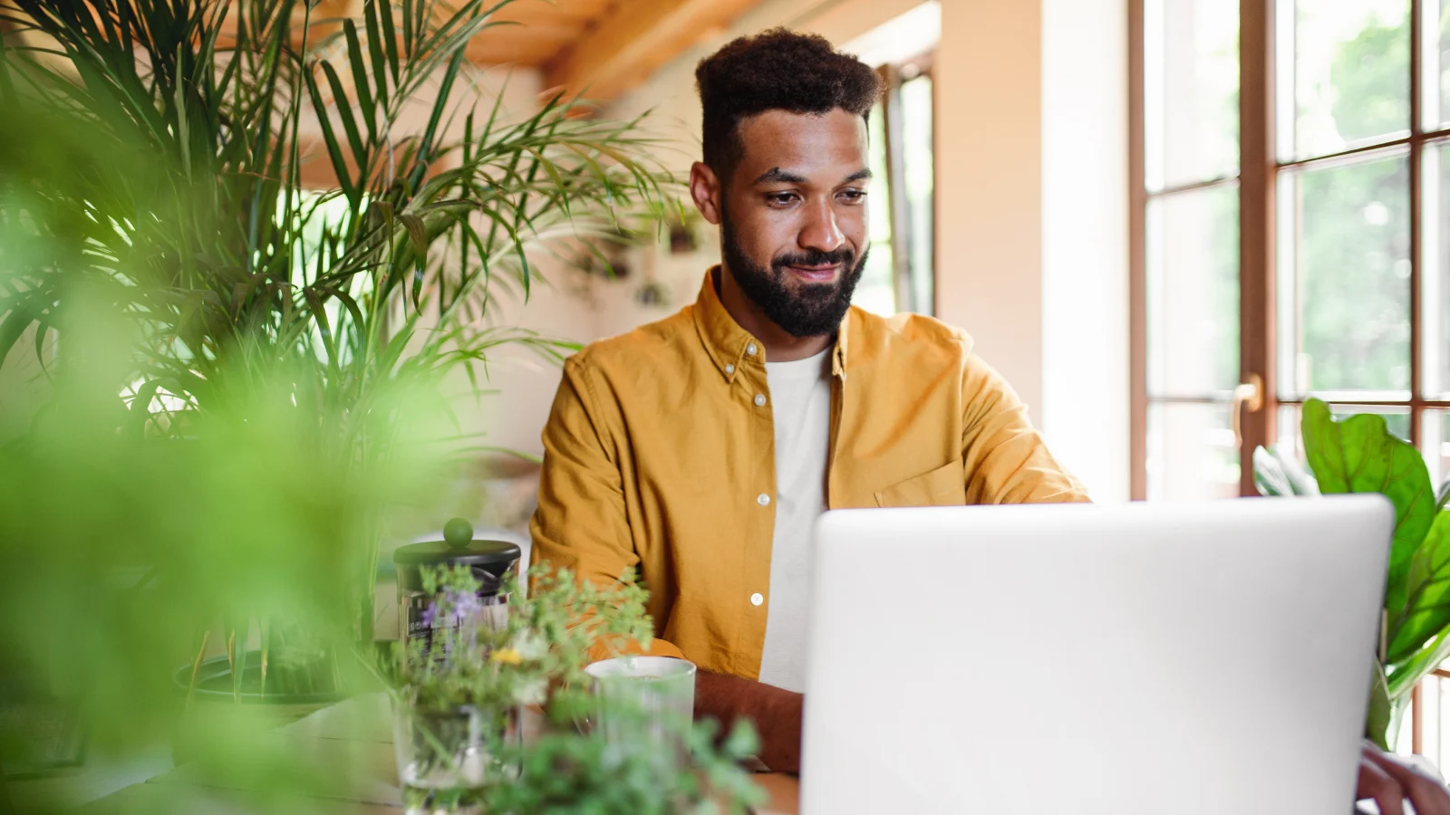 young man with laptop and coffee working indoors