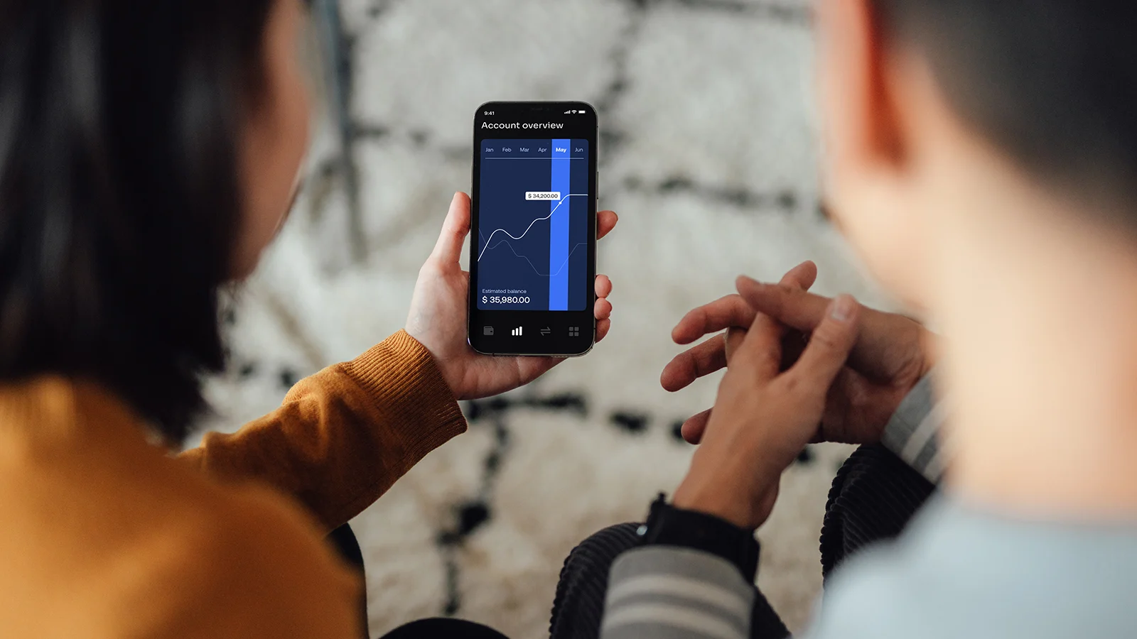 Over the shoulder view of couple managing with mobile banking app on smart phone
