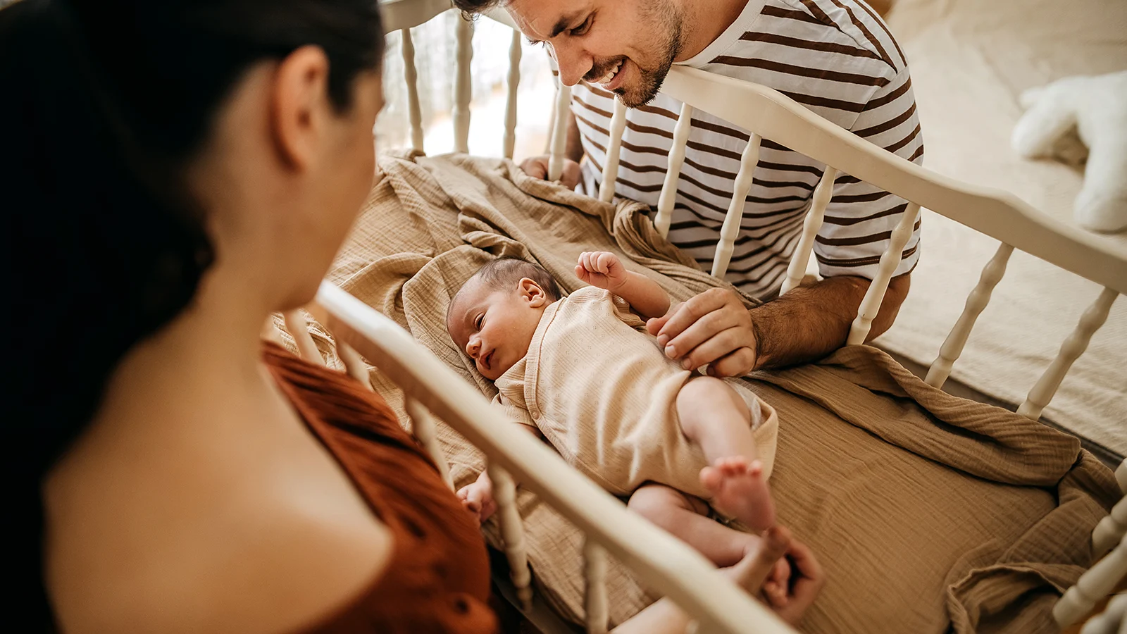 Hospital indemnity insurance - A mother and father looking at their baby in a crib