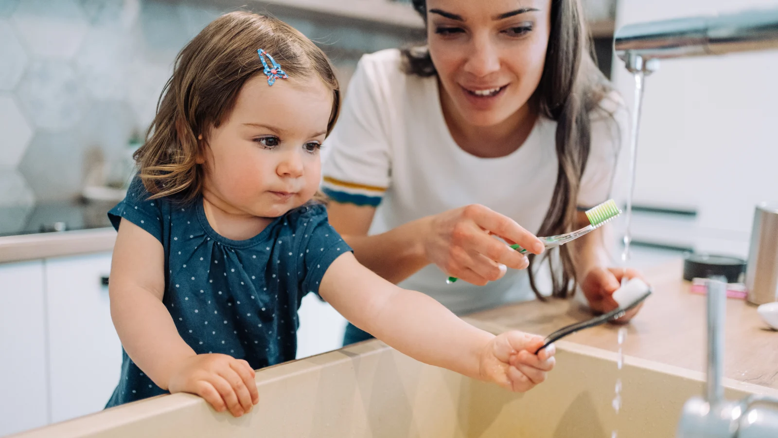 Little girl and mother brushing their teeth