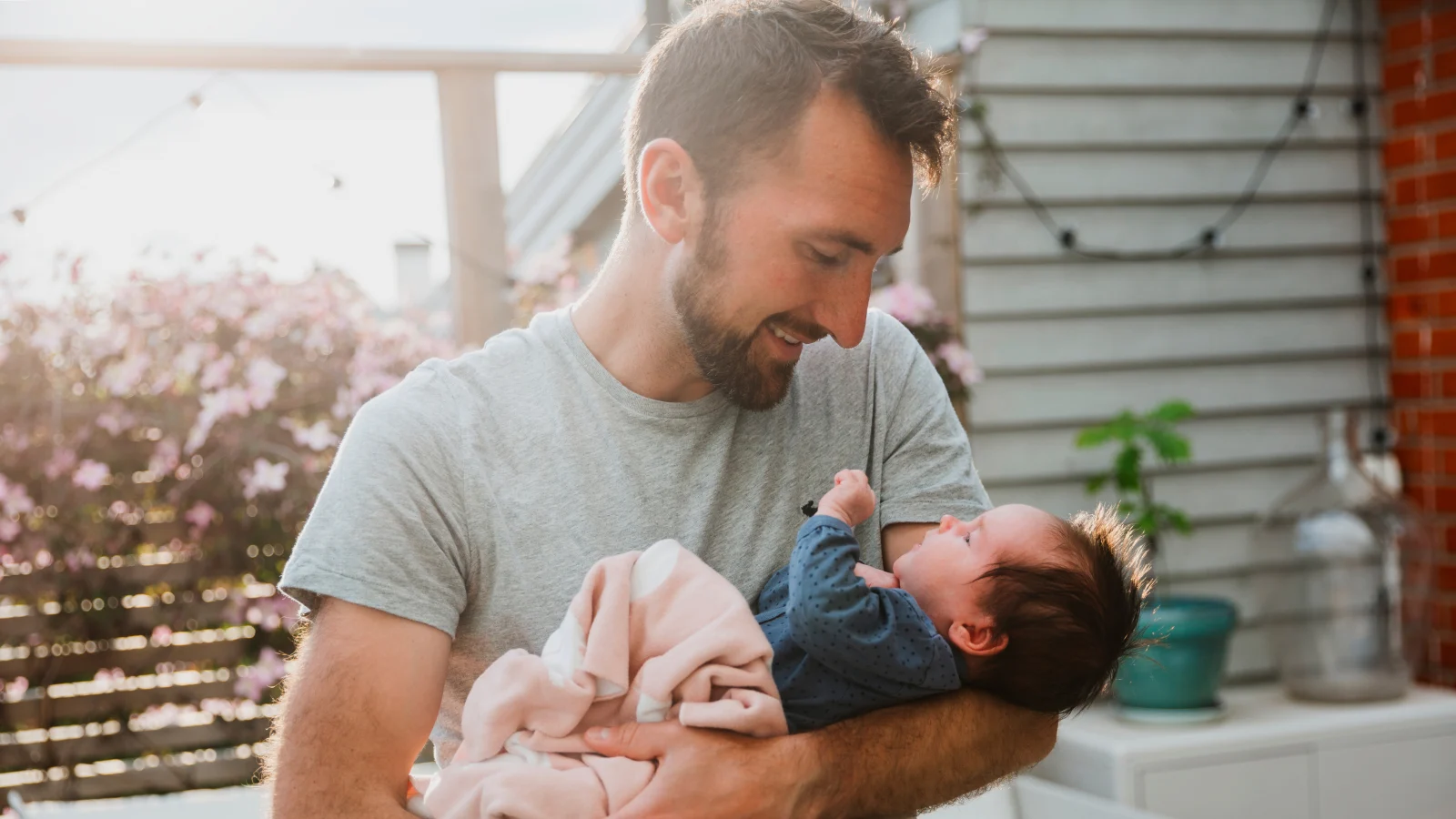 6 financial strategies to help plan for parenthood - A man holding his newborn baby at home.