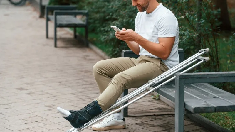 man seated with crutches
