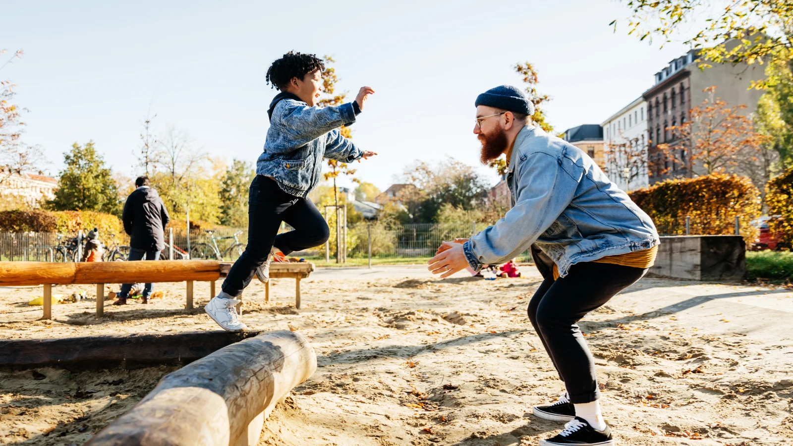 Young boy leaping into his father's arms at the playground.