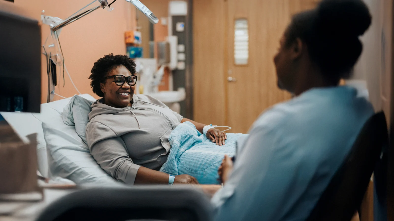 Woman in hospital bed speaking with a registered nurse.