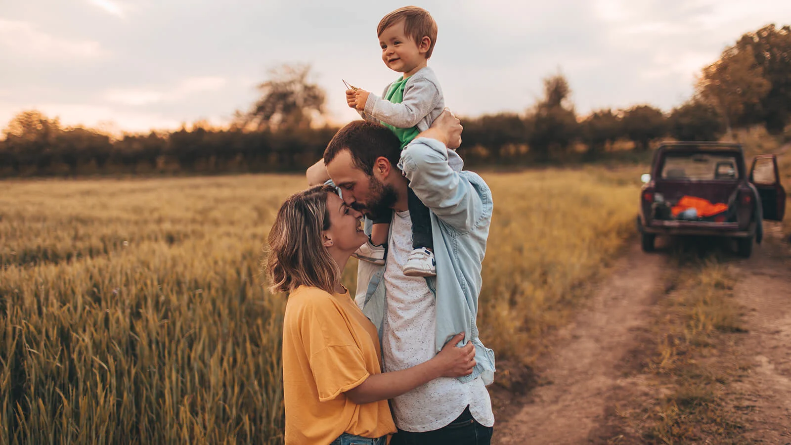 Prepared and Protected: How life insurance supports financial wellness for those you love - Young son on fathers shoulders while hugging the mother