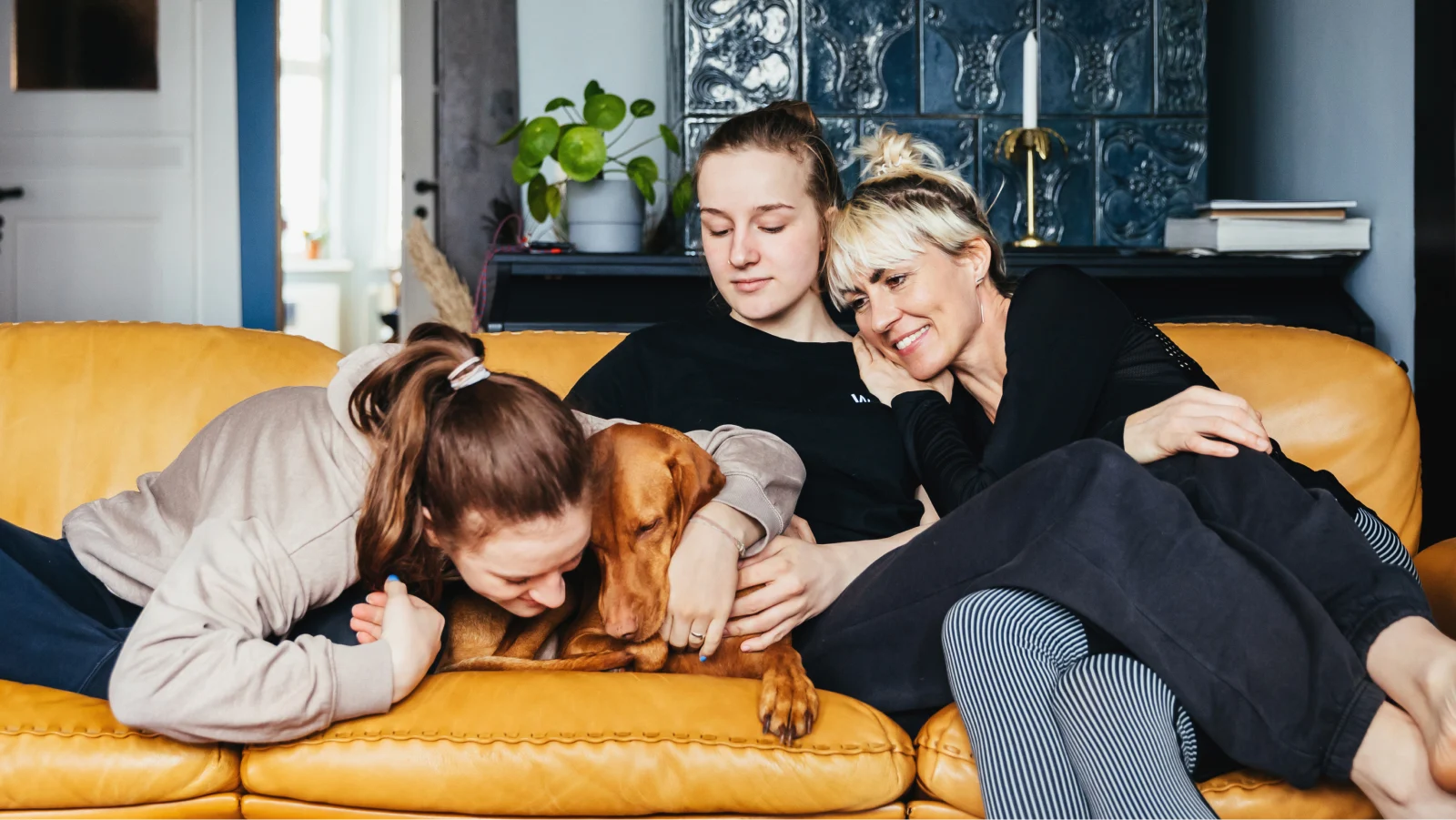 Tips on caring for caregivers - Mother and her two daughters petting their dog on the couch