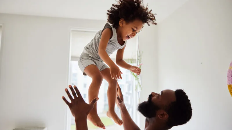 Whole life insurance - Dad tossing laughing son while playing