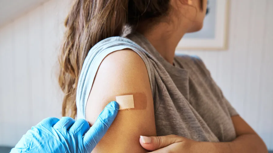 Questions about the COVID vaccine and life insurance coverage - Medical professional applying a bandaid