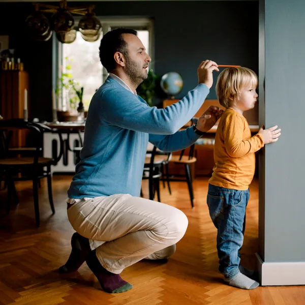 A father measuring his son's height.