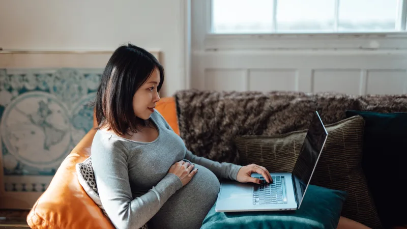 How can I protect my growing household? - Pregnant woman researching on her laptop