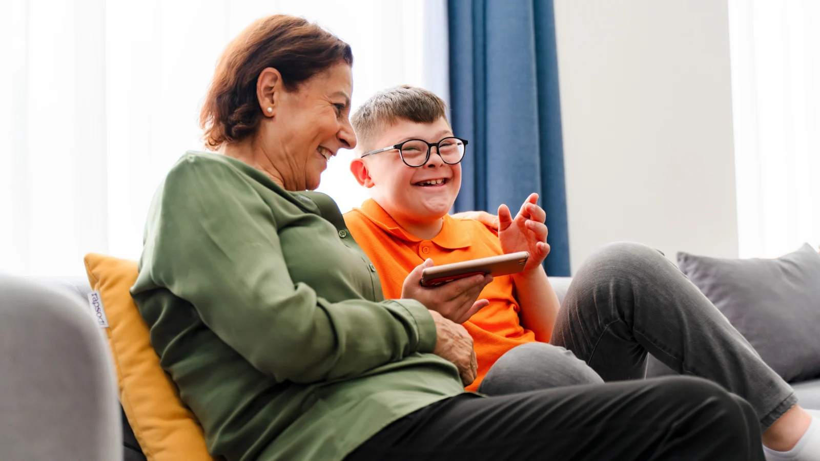 Little boy with down syndrome enjoy spending time with mother and watching mobile phone