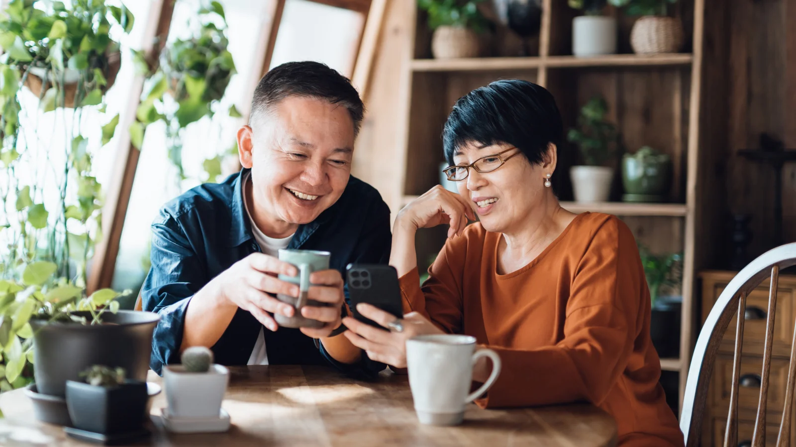 Asian couple drinking coffee and looking at a cellphone