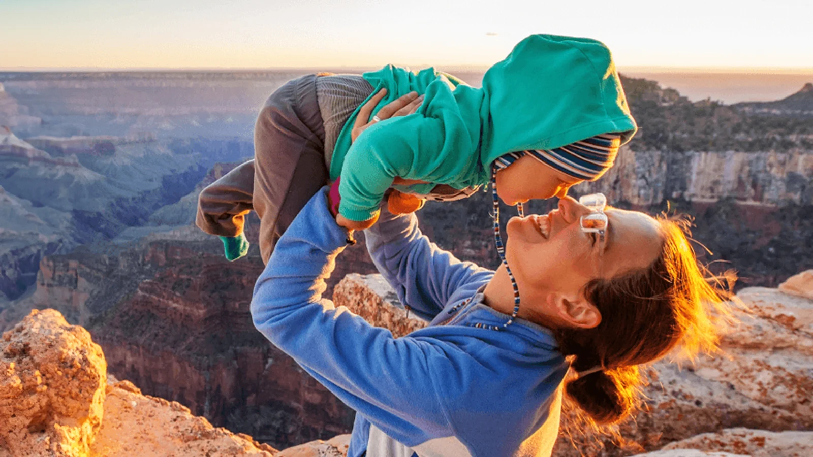 Mother holding her baby up while in the mountains