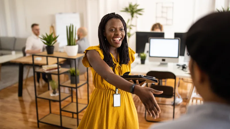 Our talented workforce is our number one asset - A woman in a yellow dress welcomes a visitor to her office with a handshake