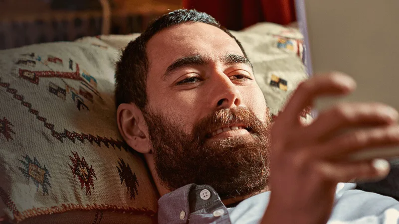 Man laying down on his bed watching his tablet