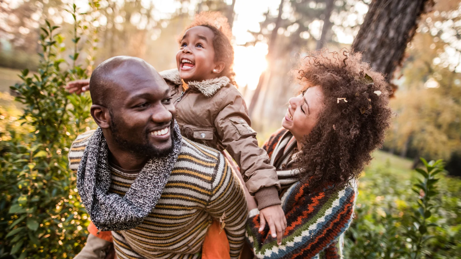 Young daughter riding the back of her father with her mother holding her