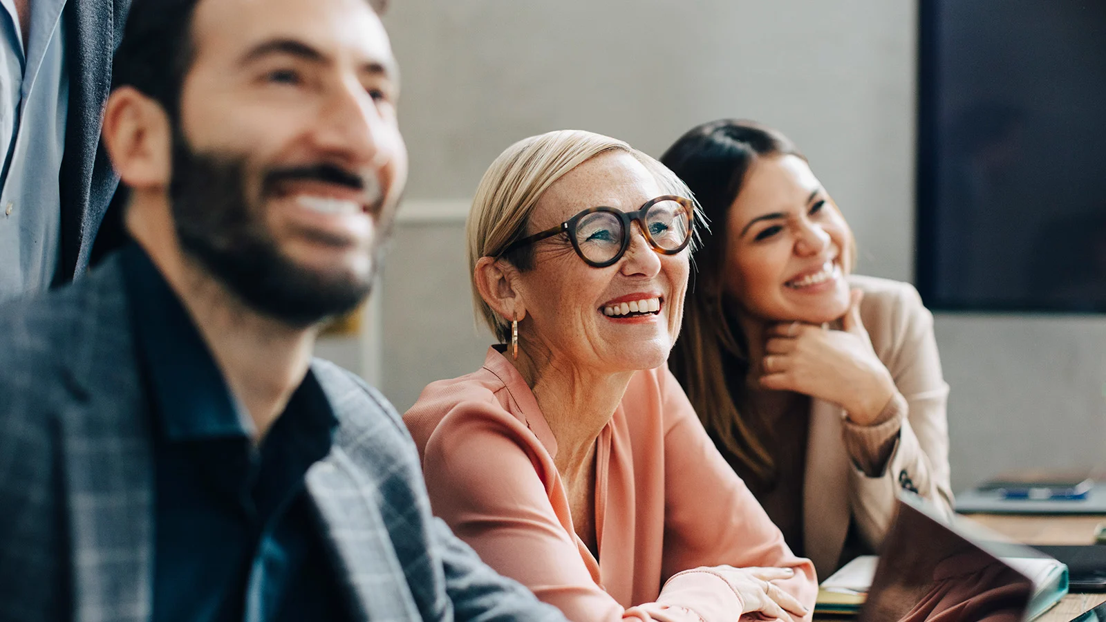 The Power of PEO Partnerships: How professional employer organizations can help their clients support employee well-being - A man and two female coworkers engaged in a presentation at work. 